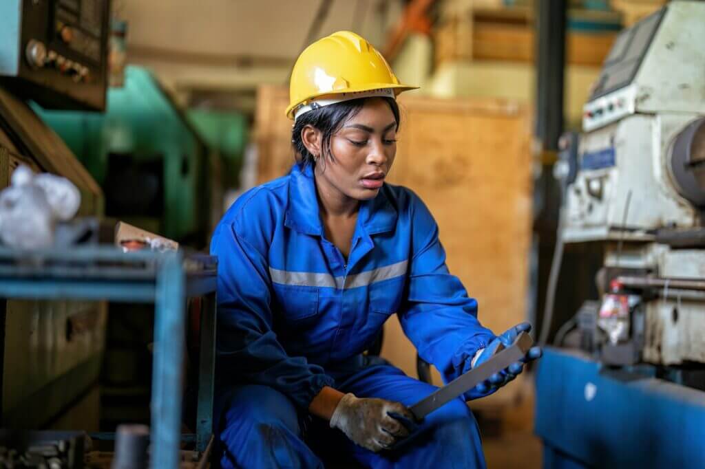 Mechanical girl in uniform on break time sitting check F wrench and heavy machinery in background