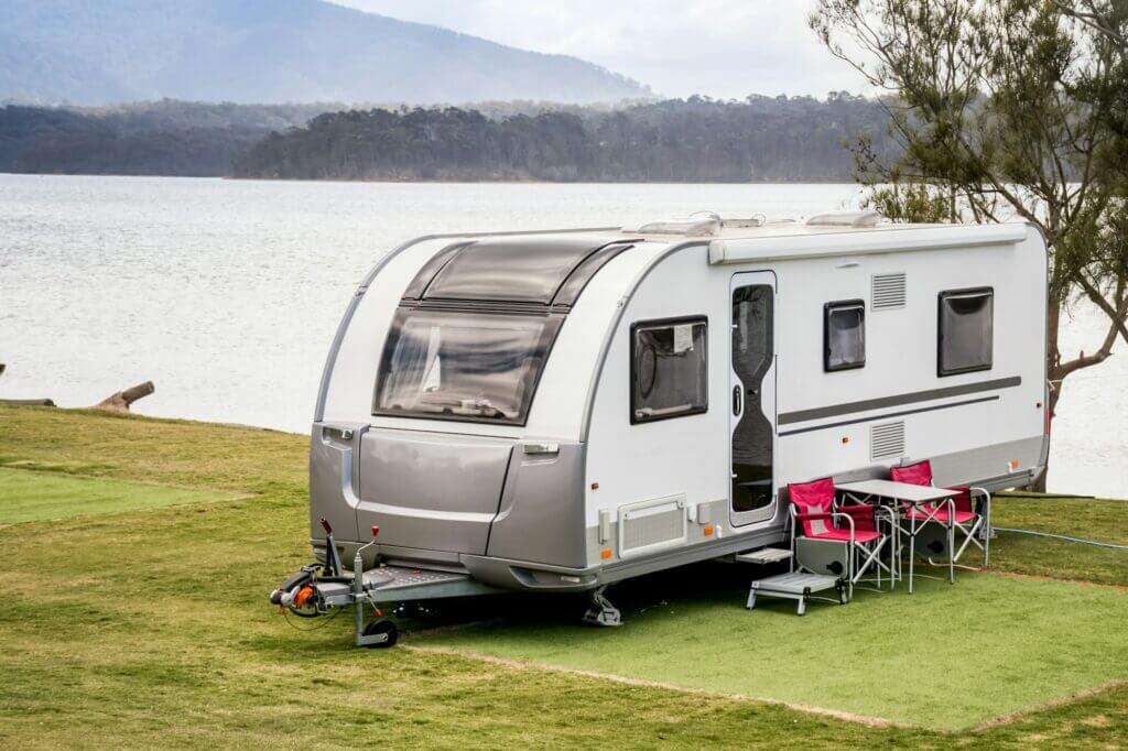 RV caravan camping at the caravan park on the beautiful lakeside with mountains on background.