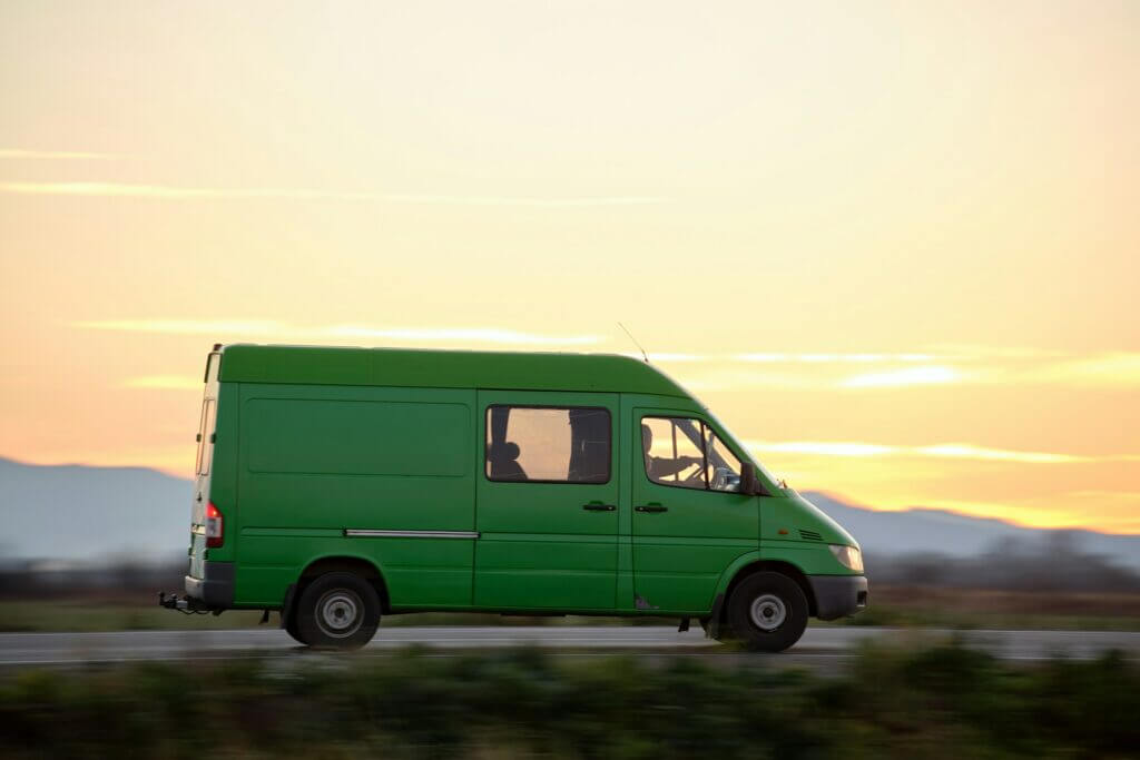 Small cargo van driving on highway hauling goods. Delivery transportation and logistics concept