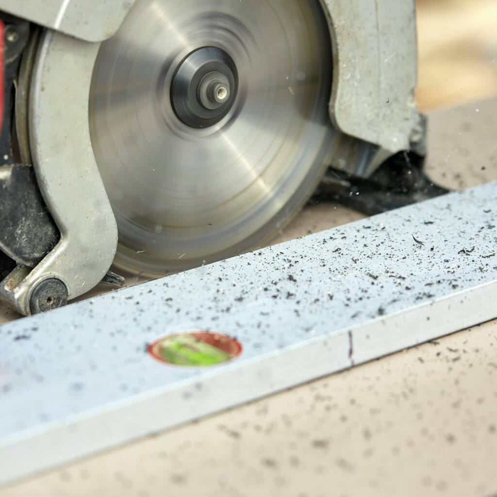 A construction contractor worker using a worm-driven hand-held circular saw to cut boards and